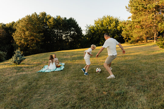 A family spends quality time outdoors with a picnic and a soccer match.