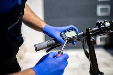 Hands adjusting digital display on electric bicycle while performing maintenance