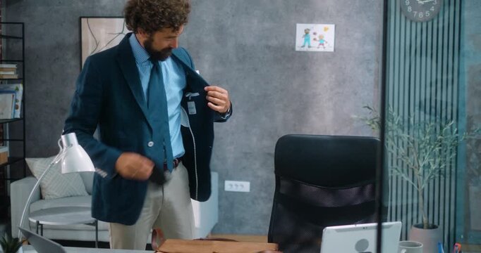 Businessman father packs up after work, gently placing his child's drawing in his bag before leaving the office for home. Part 42 of the &ldquo;Dad&rsquo;s Day&rdquo; series.