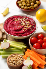 Beetroot hummus in a bowl on a board with fresh vegetables, celery, carrots, pita. Healthy food 