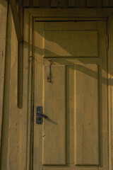 Close Up of Weathered Yellow Wooden Door with Metal Latch in Belarus