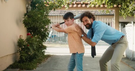 After returning from work, a businessman father teaches his young son how to play baseball in their backyard. Part 51 of the “Dad’s Day” series. - Powered by Adobe