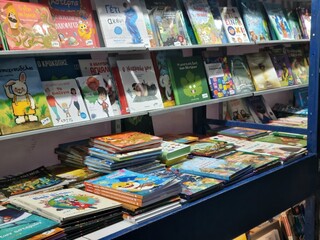 Colorful books displayed on shelves at an outdoor street market stall