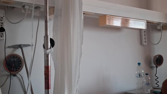 A hospital room with patient beds, medical devices, curtains, and IV equipment