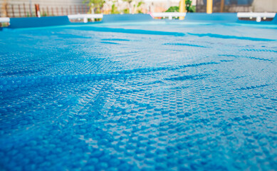 The blue coating of the pool, reflecting sunlight, emphasizes summer recreation and pool maintenance.