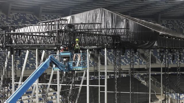 Music concert stage set up buildup construction. stadium football pitch being prepared to host a music concert. sports stadium as technicians set up the stage for the live music event.