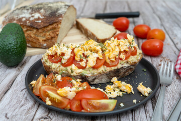 Delicious avocado toast with scrambled eggs and tomatoes