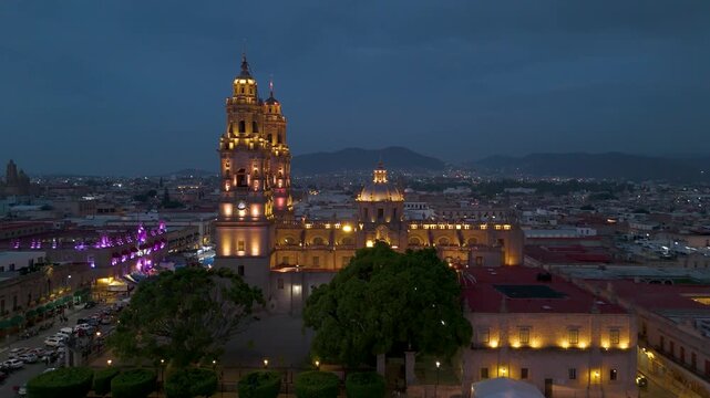 Morelia, Mexico: Beautiful aerial shots around Morelia Cathedral at nightfall. The exterior lights of its bell towers come on, illuminating it aesthetically.