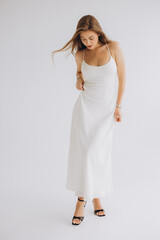 Fashion model posing in white dress and black high heels on white background