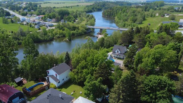 Aerial view of the renowned Mitis River with a passage under the On&eacute;sime-Gagnon road bridge where a few cars are traveling across the salmon river. Municipality of Price, Quebec, Canada, 2025.