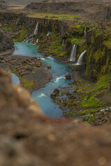 Steep Moss Covered Canyon with Turquoise River and Waterfalls in Iceland