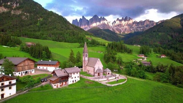 Italy Dolomites Aerial 4K Video Scenic Santa Maddalena Village in Val di Funes Smooth Drone Flight with Green Meadows and Majestic Odle Peaks Rocks South Tyrol Alpine Nature Landscape Travel