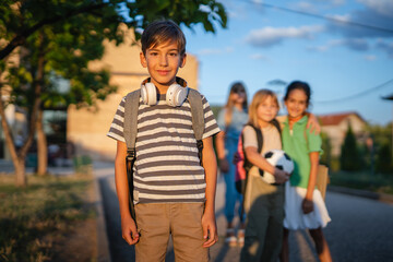 Obraz premium Boy wearing headphones and backpack standing with friends after school