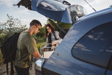 Hikers unpacking gear from car trunk before hiking trip