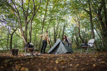 Couple setting up tent while camping in forest