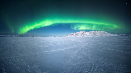 A vast landscape of snowy, icy plains stretches out against a backdrop of snow-capped mountains. Bright green northern lights illuminate the night sky.
