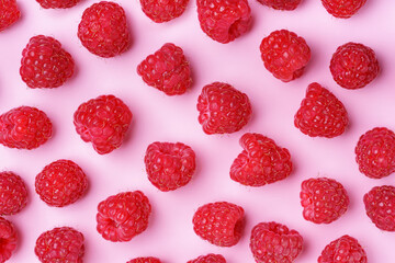 Scattered ripe red raspberries on pastel pink background. Flat lay, top view. Colorful minimal food composition, food design. Perfect for healthy eating and summer fruit, harvest concepts.