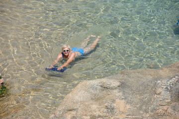 Elderly woman is posing in transparent clear sea water.