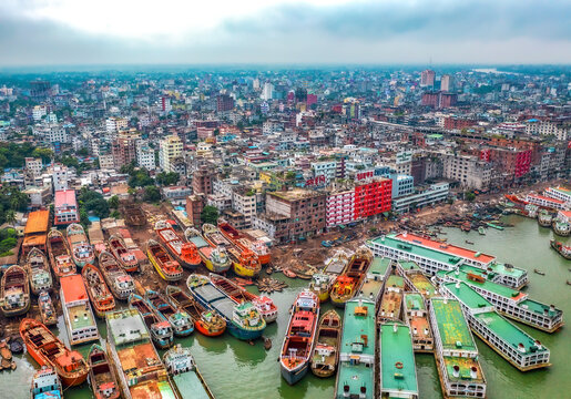Aerial view of a dense array of colorful boats clustered together on the waterway, framed by the urban sprawl, Keraniganj, Bangladesh.