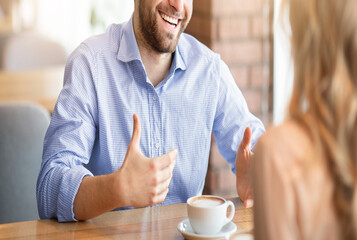 Happy young guy talking to his girlfriend while having coffee at cafe. Couple on romantic date, having friendly conversation, flirting with each other. Lifestyles and relationships concept, cropped
