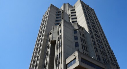 Obraz premium Majestic Brutalist Skyscraper Ascends Towards Clear Blue Sky Symbolizing Urban Ambition and Architectural Strength