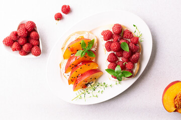 Assortment of homemade juicy sandwiches with cream cheese, peach, raspberry, chocolate paste, aromatic herbs and seeds on light stone table top view.