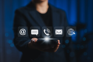 Fototapeta premium Contact Us and Customer Support Service Concept. Businessperson holding smartphone with contact icons, including email, phone, chat, and web symbols, digital customer service, communication channel,