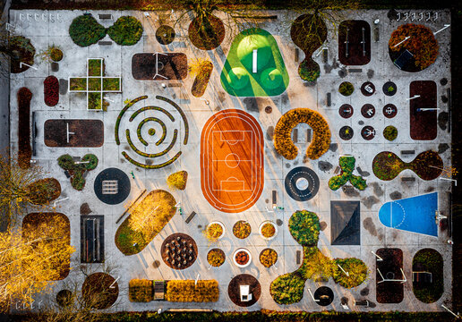 Aerial view of a vibrant playground with geometric shapes, colorful surfaces, and playful arrangements of trees and bushes, Various places, Poland.