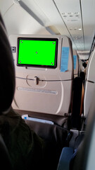 View from a passenger seat inside a commercial airplane cabin. The seatback in front has an...