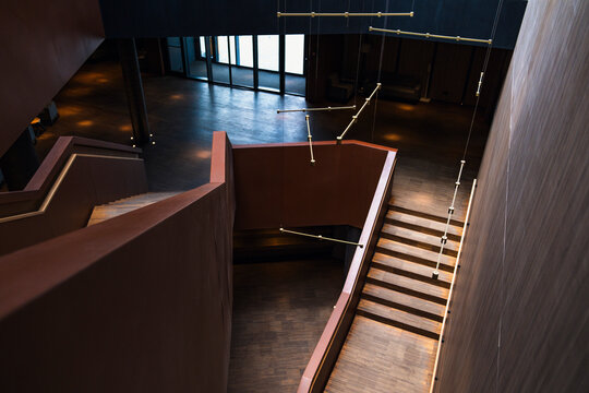 A striking high-angle view of a modern, multi-level staircase with a geometric light fixture, showcasing the elegant and sophisticated design of a contemporary building's interior.