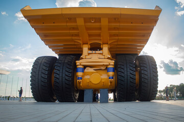 Rear view of giant yellow mining dump truck with huge tires and blue sky © Kvion