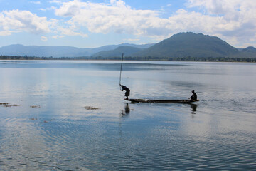 Obraz premium Two fishermen in a long, narrow canoe in a still lake in Myanmar.