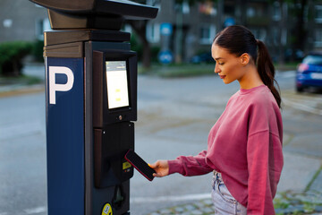 Woman driver using her cellphone for payment for public outdoors parking by NFC. Contactless...