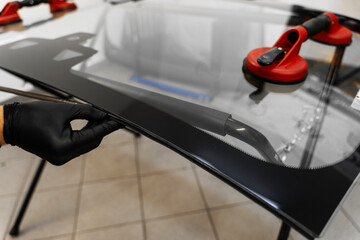 Windshield Edge Sealing Preparation. Technician prepares car windshield edge for installation....