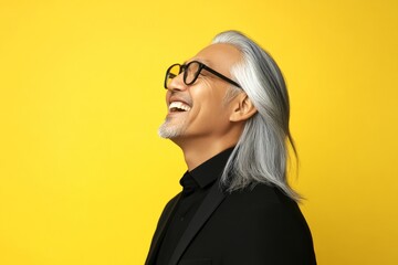 Yellow solid background. Modish men's two-block cut haircut - midlife southeast asian man with long hair. A trendy and poised male showing charm. Idea of style for aging men.