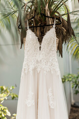 closeup of a beautiful bridal dress on a hanger in the morning of the wedding day on a palm tree