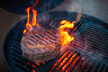 Barbecue dry aged angus tomahawk steak close-up on a charcoal grill with fire and smoke