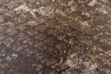 Weathered industrial metal surface with rust, scratches, and diamond plate texture. Brown and beige tones create a gritty, aged look. Ideal for backgrounds, construction themes, or texture reference.