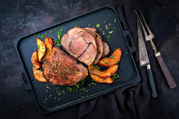 Traditional lamb leg roll roast with herbs and quince fruit served as top view on a cast iron tray