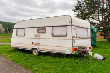 One classic white caravan with closed blinds parked on lush green campsite near Slapy lake. Peaceful rural landscape ideal for camping and nature tourism. Copy space.