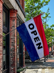 A red, white, and blue open flag on the side of a brick building