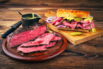 Traditional sliced cold cuts roast beef sandwich with onion, gherkin and onion served as close-up on a wooden board