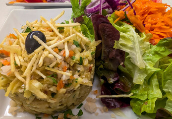 Top view of Portugal dish Bacalhau a Bras (shreds of salted cod, onions and thinly chopped fried potatoes, together with colourful salad.