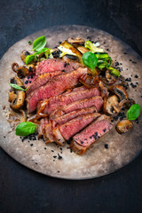 Traditional barbecue grass-fed dry aged roast beef steak  with mushrooms and greens served as close-up on a rustic plate