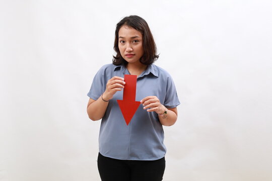Sad asian young woman standing while holding red arrow down. Concept of loss and stock market crash