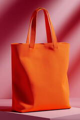 Vibrant orange cotton tote bag standing upright on pink studio background with shadows, eco-friendly reusable shopping bag for modern minimalist lifestyle concept