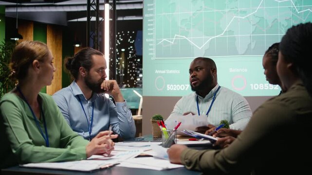 Specialists team presenting the financial data on documents to the team, preparing for upcoming shareholders briefing meeting. Exchanging information and delivering forecasting updates. Camera A.