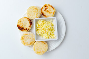 Traditional Colombian and Venezuelan arepas, homemade white corn cakes served with shredded cheese for breakfast or as a snack, a typical gluten-free dish from South America, on a white background