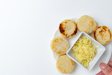Traditional Colombian and Venezuelan arepas, homemade white corn cakes served with shredded cheese for breakfast or as a snack, a typical gluten-free dish from South America, on a white background