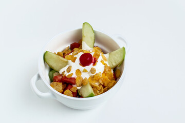 Colombian fruit salad (Salpicón or Copa de Frutas) with fresh apple, cherry, corn flakes, and yogurt cream, a healthy and refreshing dessert or breakfast bowl isolated on a white background.